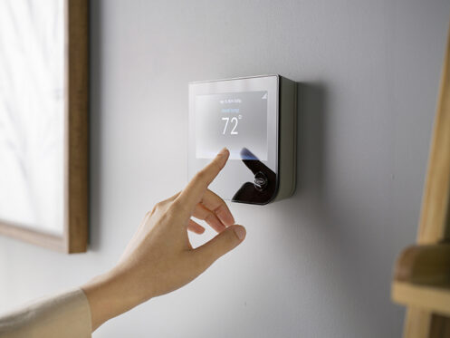 A woman checking the smart thermostat.